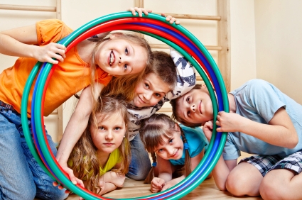 Portrait of laughing children looking through hula hoops